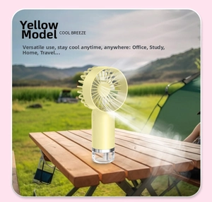 Yellow portable handheld mist fan on a wooden table for outdoor camping use