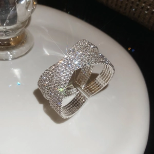 Gros plan d'une bague croisée en argent à double couche avec pavé de zircons sur plateau blanc
