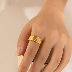 Detailed view of a gold geometric rectangular link ring on a female model's finger