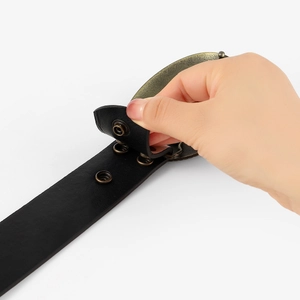Close-up of vintage black leather belt featuring bronze alloy buckle and adjustable holes