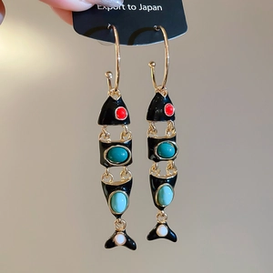 Close-up of vintage fish tassel C-shaped earrings with colorful enamel and gold finish