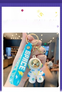 Detail view of cartoon astronaut keychain with gold face shield and blue 'SPACE' strap
