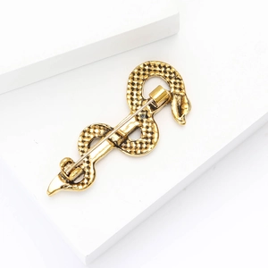 Detailed macro view of a gold snake-shaped brooch showing realistic scale textures and pin