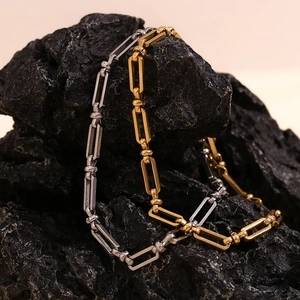 Detailed macro view of gold and steel paperclip link anklets on a dark volcanic rock