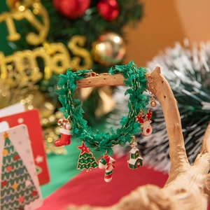 Close-up of Christmas charm bracelet with festive pendants hanging on a wooden branch