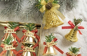 Close-up of golden Christmas bells with red bows and green pine needles in a festive box