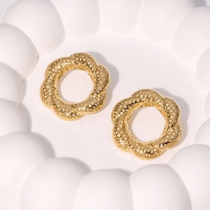 Textured hammered 18k gold plated stainless steel floral wreath earrings on white plate