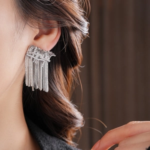 Gros plan de boucles d'oreilles pendantes à pampilles argentées portées par un mannequin