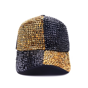 Close-up of a gold and black sequined baseball cap with a luxury checkerboard rhinestone pattern