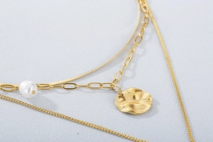 Detailed macro view of gold multi-layer necklace with pearl and hammered round pendant