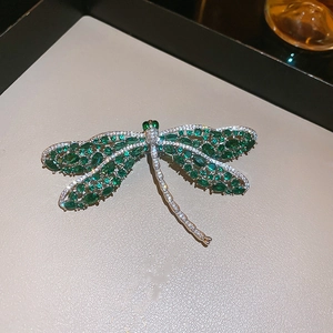 Detail van de libellenbroche met groene stenen en fonkelende kristallen in close-up