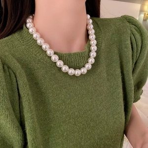 Gros plan détaillé de grosses perles blanches rondes sur un collier de style vintage