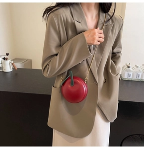 Close-up of a red apple-shaped mini crossbody bag with green leaf detail and gold chain
