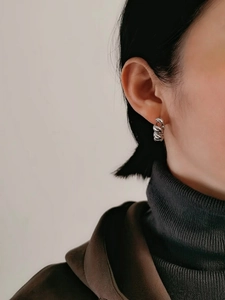 Detailed close-up of a silver S925 sterling silver twisted rope hoop earring on a model
