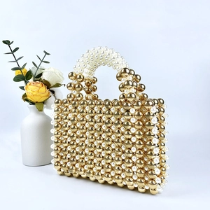 Detailed view of handmade beaded handbag with gold and white pearls and curved handles