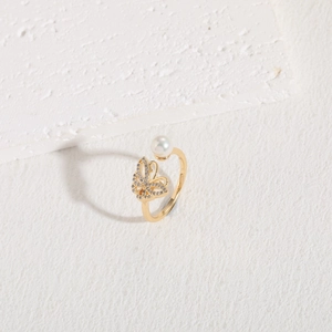 Detailaufnahme des goldenen Schmetterlingsrings mit Zirkonia und runder weißer Perle