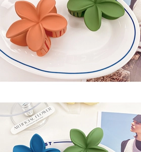 Detail showing matte plumeria flower hair claws in orange, green, and blue colors