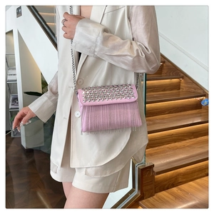 Pink crossbody bag featuring silver studs and long fringe detail on a metal chain strap