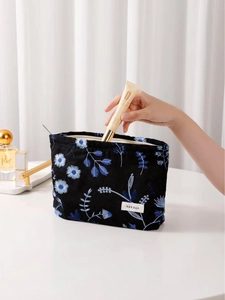 Black canvas makeup bag with blue daisy embroidery and silver zipper for storage