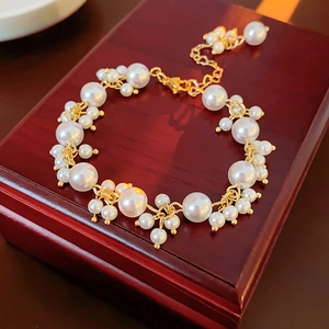 Close-up of pearl bracelet with gold metal accents on dark red wooden gift box