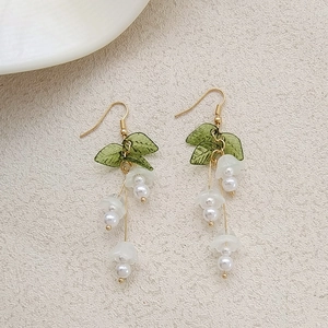 Close-up of pink lily of the valley earrings with green resin leaves and white pearls