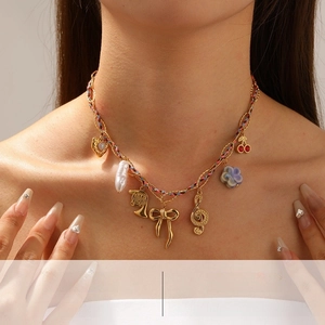 Detail of gold chain necklace with colorful braided rope, heart and musical note charms