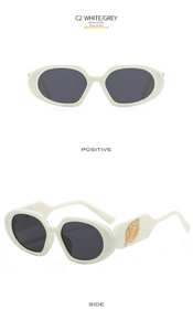 Detail of white oval sunglasses featuring golden leaf metal decor on the side temple