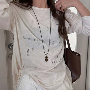 Chic resin gourd necklace with deep brown pendant and black cord on cream sweater