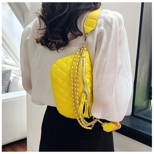 Detail of yellow quilted crossbody bag with gold chain and woven strap on model