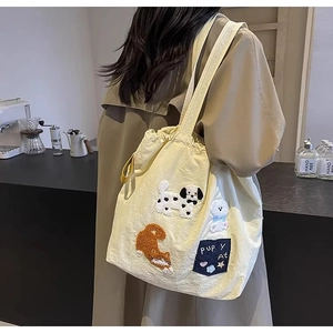 Detail of canvas tote bag featuring plush cartoon dog embroidery and soft texture