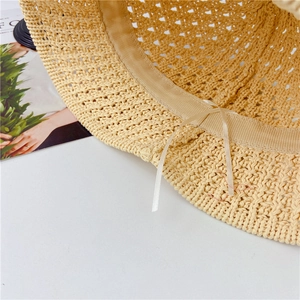 Detail of hollow-out woven straw hat featuring adjustable sweatband and drawstring cord