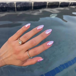 Faux ongles rose perle chromé avec bagues en diamant doré sur fond d'eau de piscine