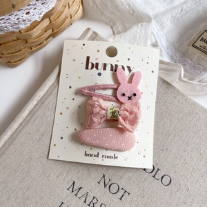 Detailed view of pink fabric bunny hair clips with lace bows on a vintage book
