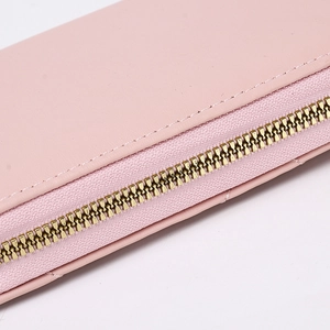 Close-up of golden zipper on pink leather wallet with quilted pattern detail