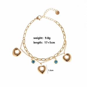 Detail view of gold double-layer bracelet with hollow hearts and blue evil eye pendants