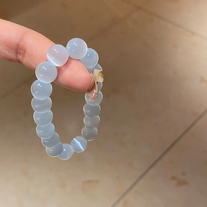 Detailed macro view of light blue cat-eye beaded bracelet featuring a gold butterfly charm