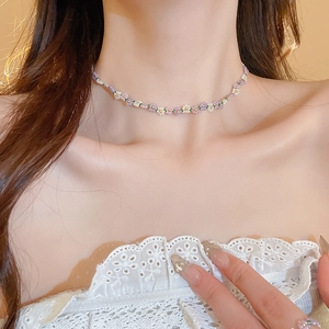 Close-up of a pastoral beaded flower necklace in purple and white on a female model