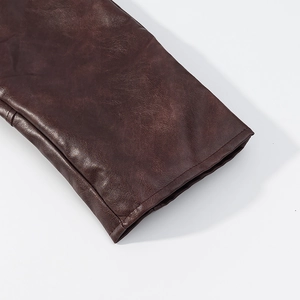 Gros plan de la manche d'une veste en cuir marron foncé avec coutures et texture