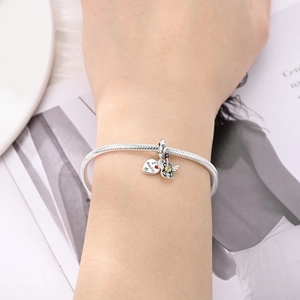 Close-up of silver snake chain bracelet with heart and guitar music charms on wrist