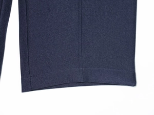 Gros plan sur la texture du tissu sergé bleu marine et les coutures de l'ourlet du pantalon