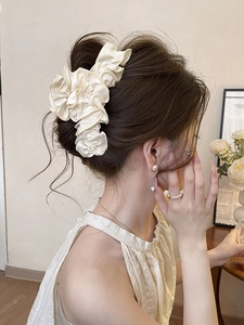 Détail de la pince à cheveux élégante en satin plissé crème avec une texture soyeuse