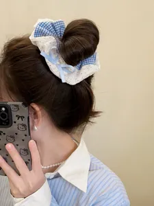 Detail of blue plaid lace scrunchie with bow ribbon and faux pearl accent on model