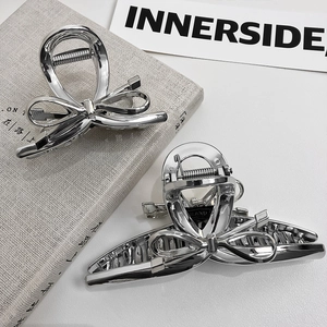 Silver bow-shaped metal hair claw clips with metallic finish on a minimalist background