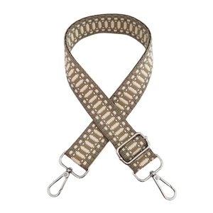 Detail of geometric beige and dark coffee woven shoulder strap with silver metal hooks