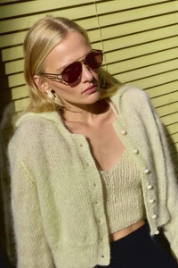 Detail of mint green mohair knit cardigan set with matching buttons in soft sunlight