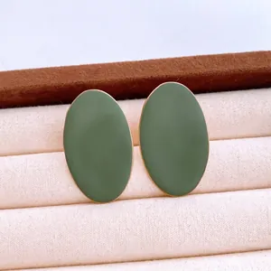 Minimalist olive green oval earrings with gold trim displayed on a cream velvet box
