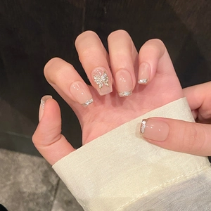 Unghie finte nude con punte glitter argento e ciondolo a farfalla dorato 3D