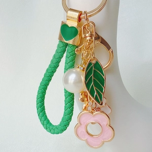 Leaf flower keychain with green woven strap and rhinestone heart pendants on hand