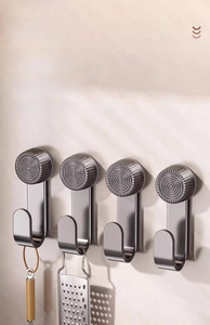 Detail of four gunmetal stainless steel hooks for pot lid storage on marble wall