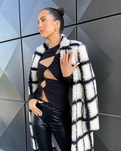 Close-up showing texture of black and white plaid plush coat with faux leather leggings
